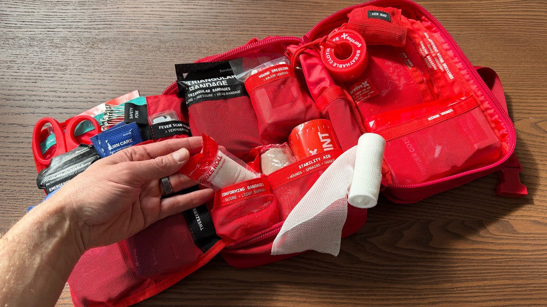 Open SurviveX first aid kit with gauze rolls, sterile pads, and cohesive wrap